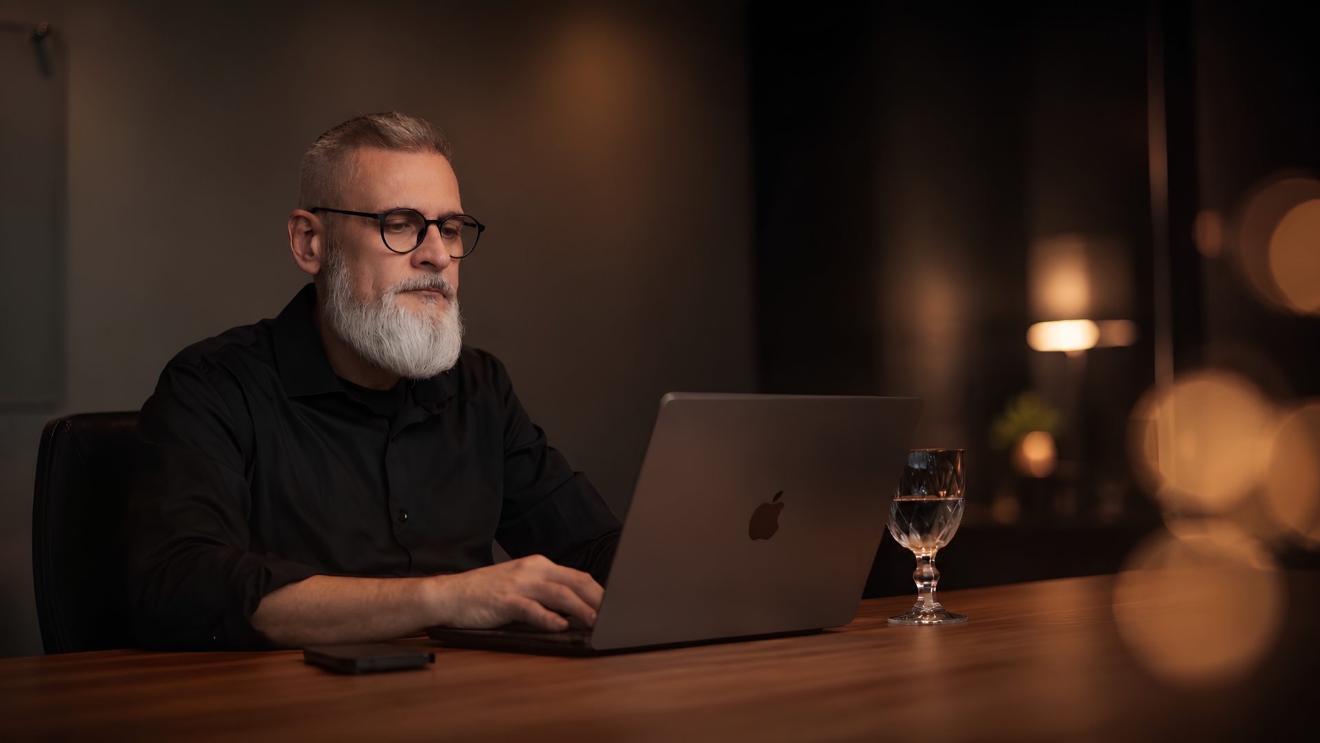 Alexandre Pscheidt trabalhando em seu notebook, em ambiente com iluminação quente